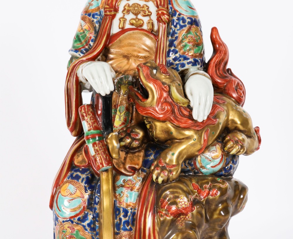 An antique Japanese Kutani porcelain sculpture depicting Guanyin standing beside a shishi lion with detailed polychrome drapery and gold leaf accents. View IV
