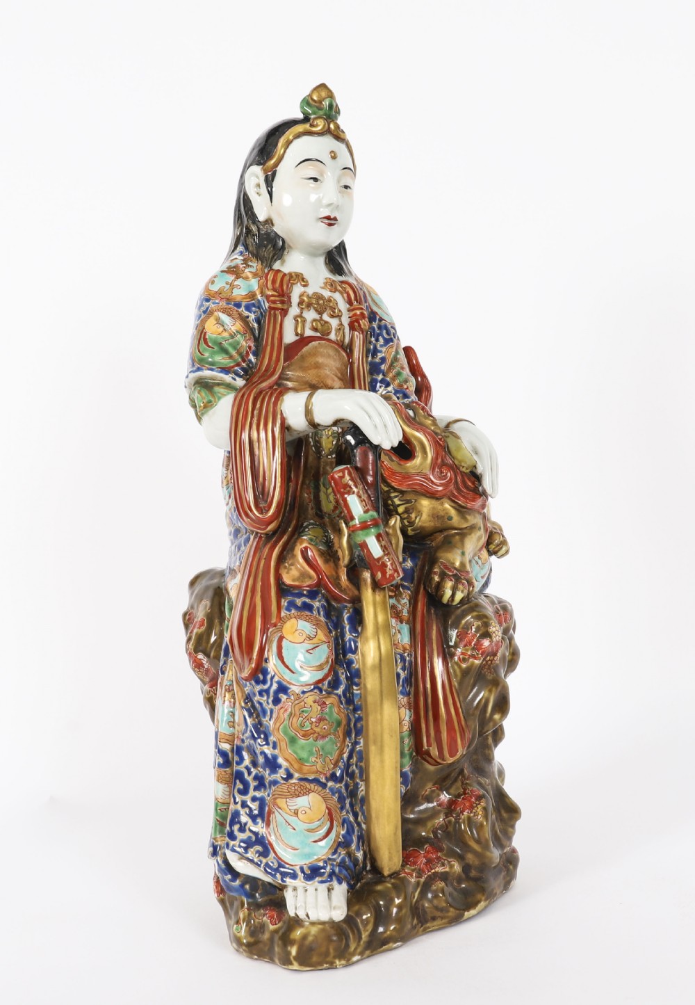 An antique Japanese Kutani porcelain sculpture depicting Guanyin standing beside a shishi lion with detailed polychrome drapery and gold leaf accents. View X