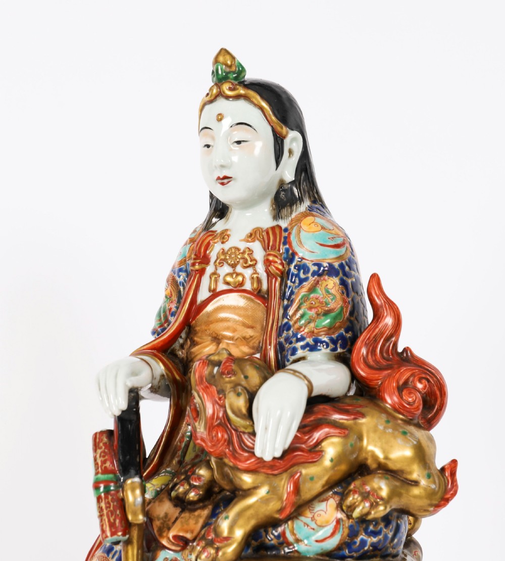 An antique Japanese Kutani porcelain sculpture depicting Guanyin standing beside a shishi lion with detailed polychrome drapery and gold leaf accents. View XV
