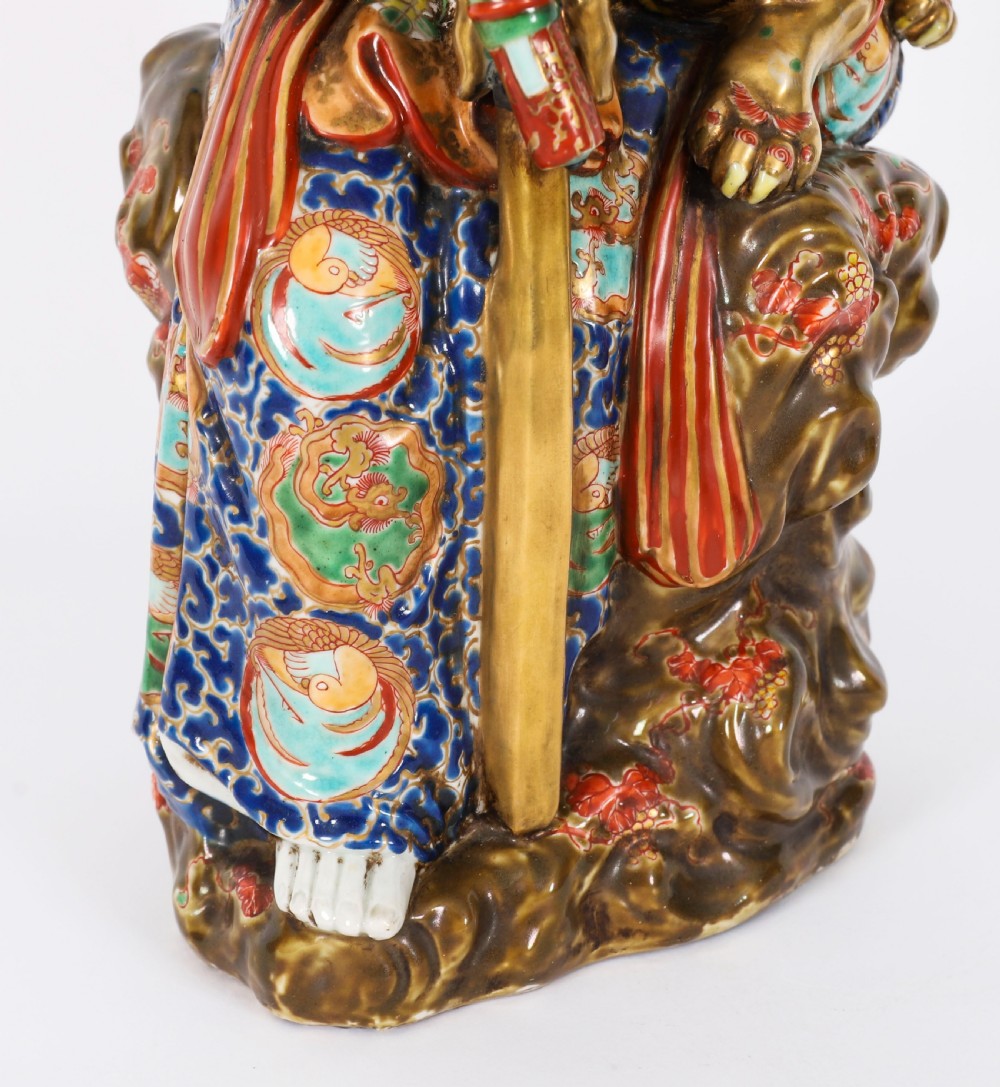 An antique Japanese Kutani porcelain sculpture depicting Guanyin standing beside a shishi lion with detailed polychrome drapery and gold leaf accents. View XVII