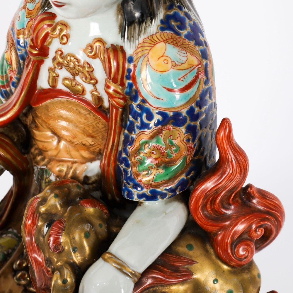 An antique Japanese Kutani porcelain sculpture depicting Guanyin standing beside a shishi lion with detailed polychrome drapery and gold leaf accents. View XIX