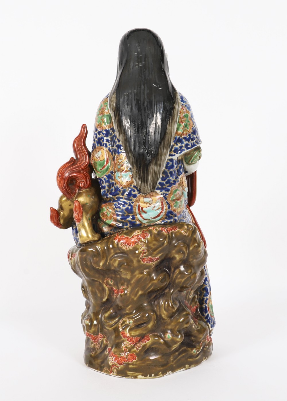 An antique Japanese Kutani porcelain sculpture depicting Guanyin standing beside a shishi lion with detailed polychrome drapery and gold leaf accents. View XX