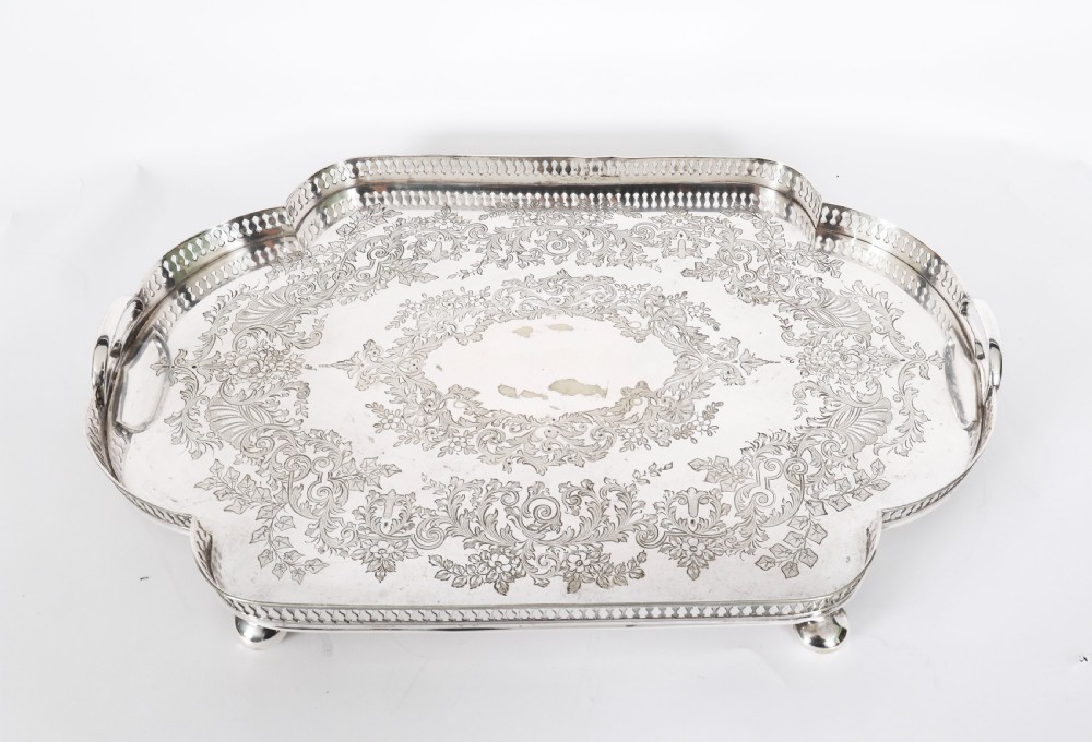 An Edwardian silver-plated gallery tray featuring a pierced rim, engraved foliate scrollwork, twin handles, and ball feet. View II