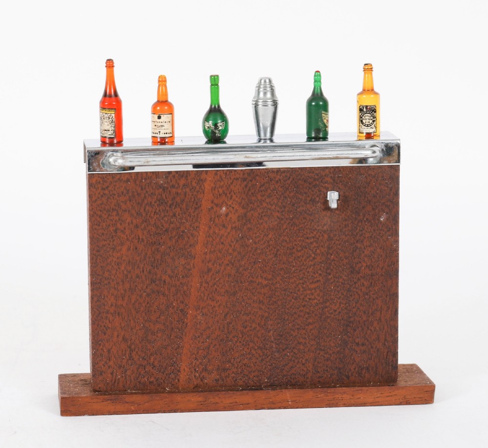 An Art Deco wooden cocktail stick holder featuring miniature liquor bottle handles and a central cocktail shaker pick atop a chrome-trimmed base. View II
