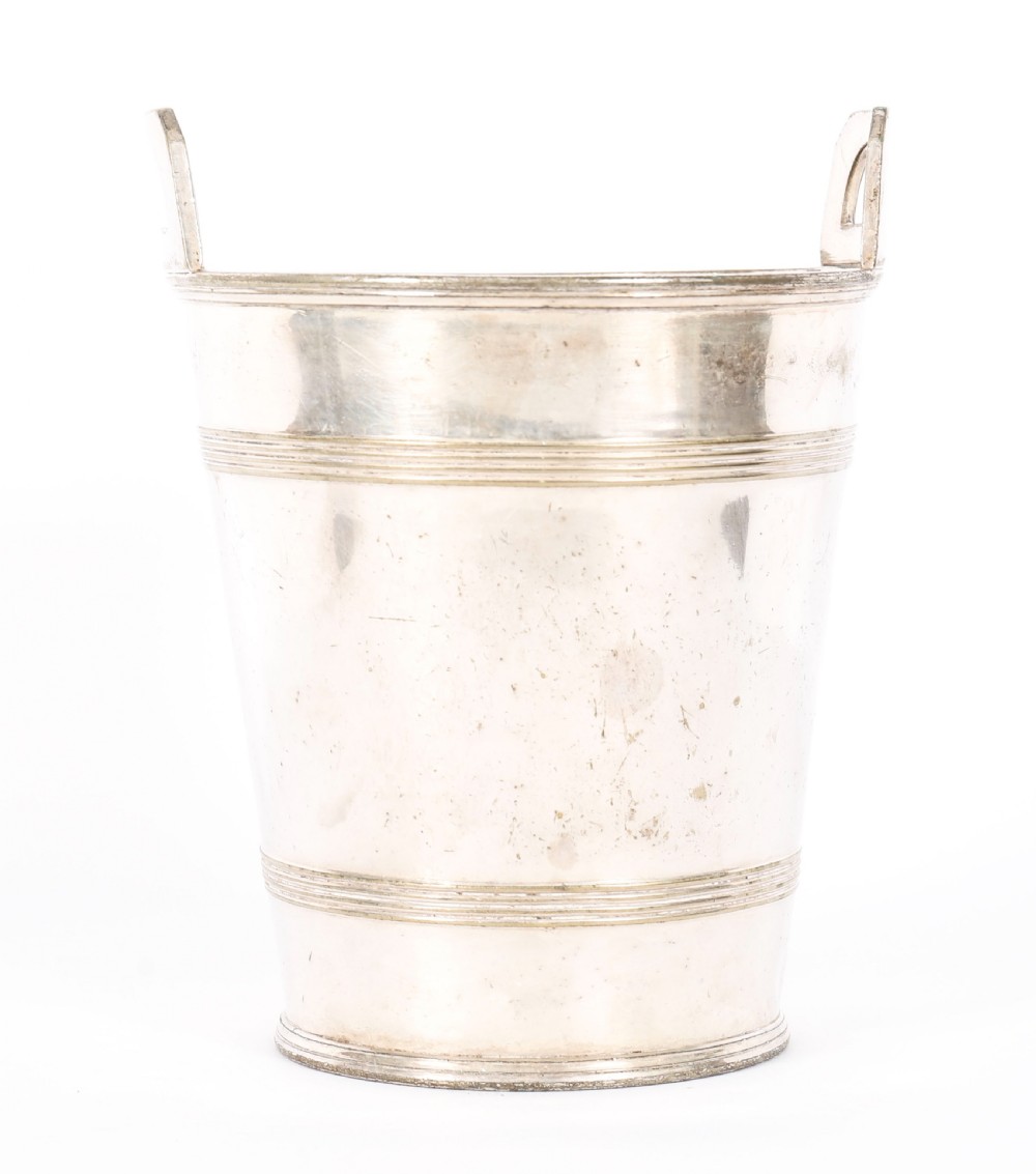 An Art Deco silver-plated champagne cooler featuring angular raised handles, horizontal reeded bands, and an engraved circular crest. View IV
