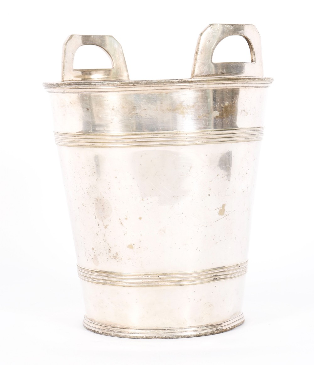 An Art Deco silver-plated champagne cooler featuring angular raised handles, horizontal reeded bands, and an engraved circular crest. View VI