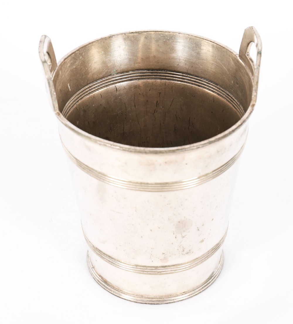 An Art Deco silver-plated champagne cooler featuring angular raised handles, horizontal reeded bands, and an engraved circular crest. View IX