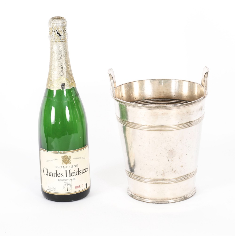 An Art Deco silver-plated champagne cooler featuring angular raised handles, horizontal reeded bands, and an engraved circular crest. View XII