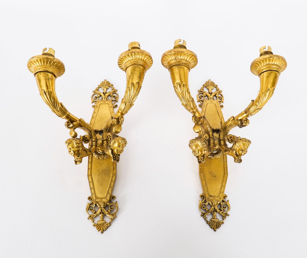 A pair of antique French Louis XIV Revival two-branch gilt bronze ormolu wall sconces decorated with cherub motifs.