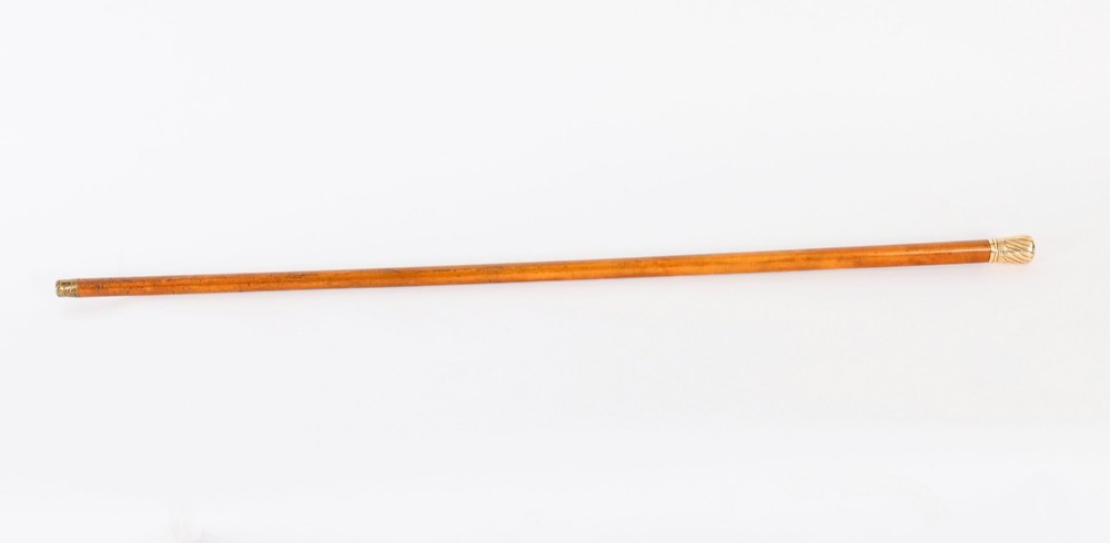 A straight polished wooden walking cane featuring a decorated 18ct gold pommel handle and a metal ferrule tip at the base.
