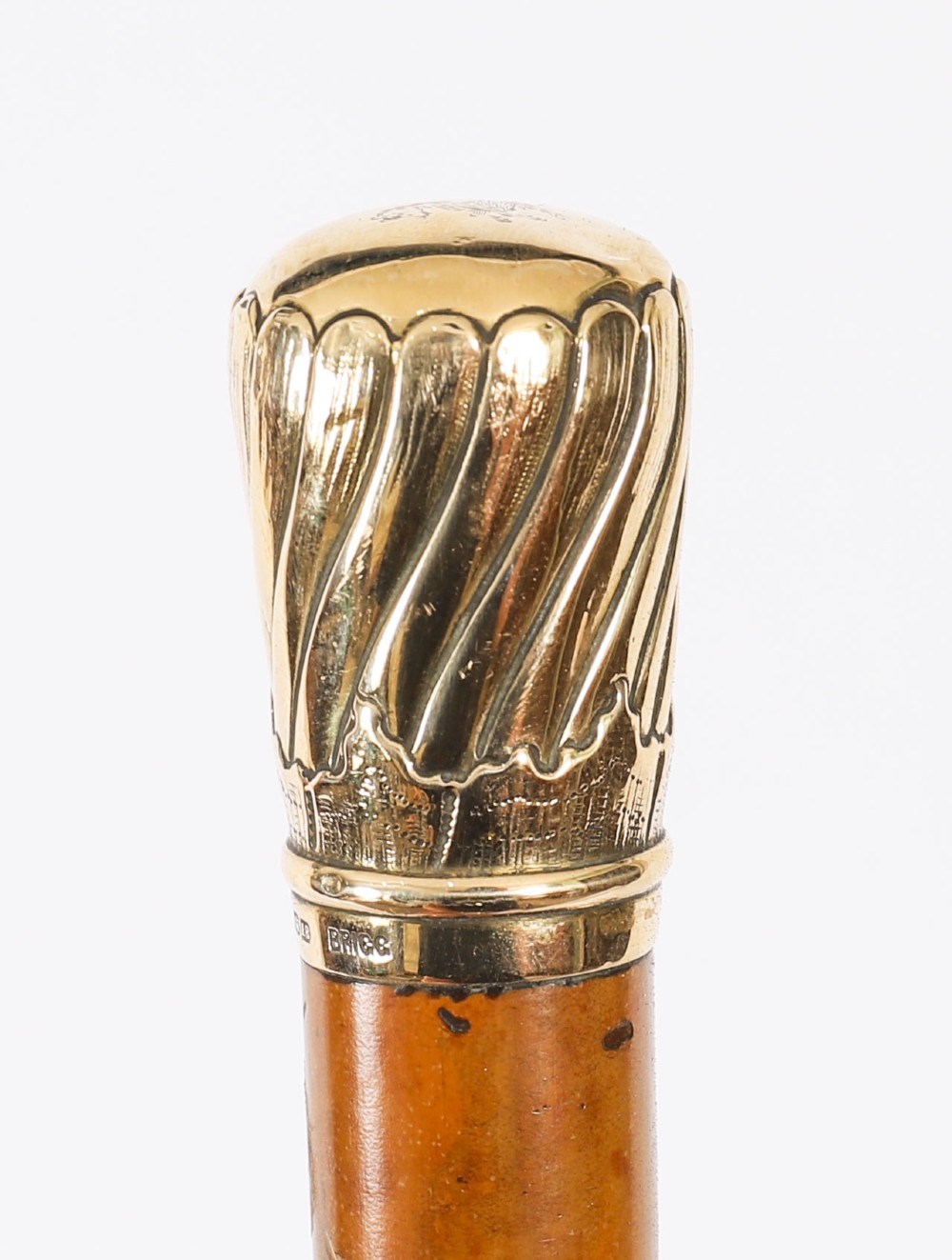 A straight polished wooden walking cane featuring a decorated 18ct gold pommel handle and a metal ferrule tip at the base. View IX