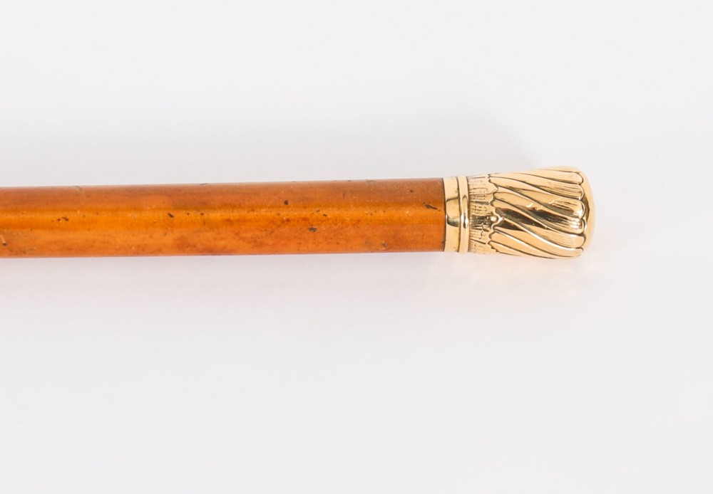 A straight polished wooden walking cane featuring a decorated 18ct gold pommel handle and a metal ferrule tip at the base. View XI