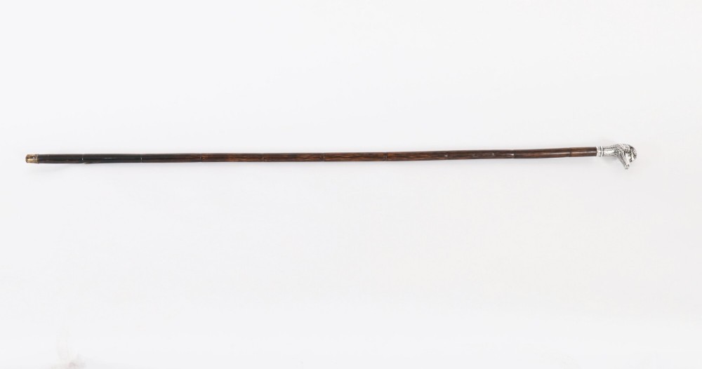 An antique walking stick featuring a dark polished wooden shaft topped with a cast silver duck head handle.