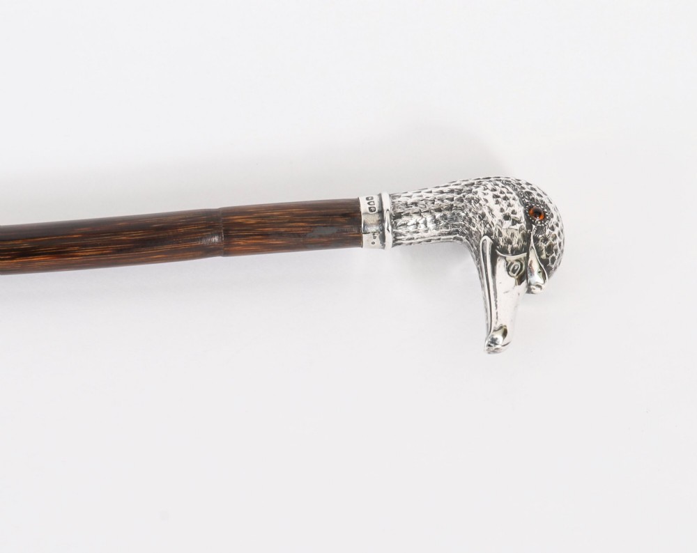An antique walking stick featuring a dark polished wooden shaft topped with a cast silver duck head handle. View V