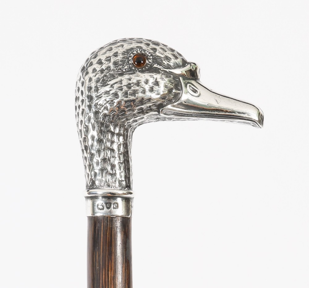 An antique walking stick featuring a dark polished wooden shaft topped with a cast silver duck head handle. View XV