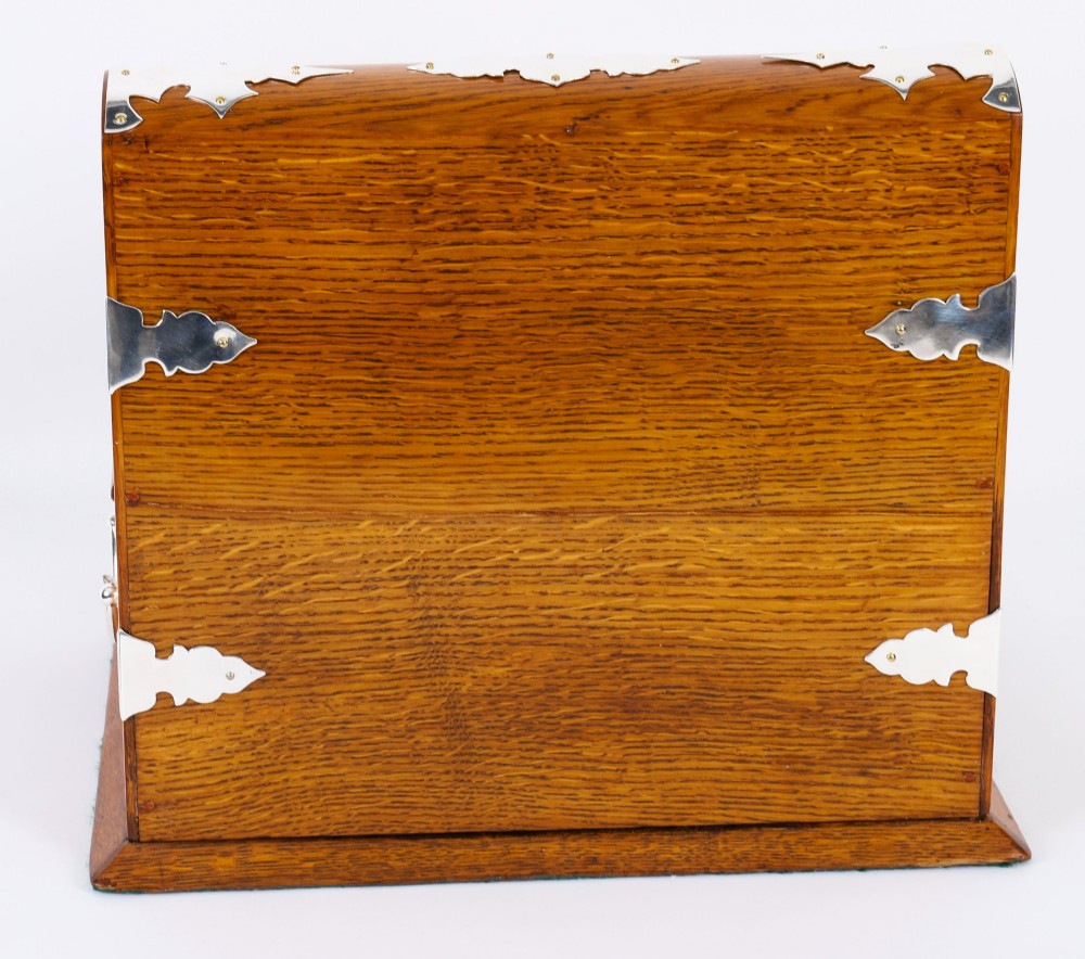 An antique blonde oak tantalus featuring three square cut-glass decanters set against a mirror back, decorative silver-plated corner mounts, and a lower drawer with a key. View XIV