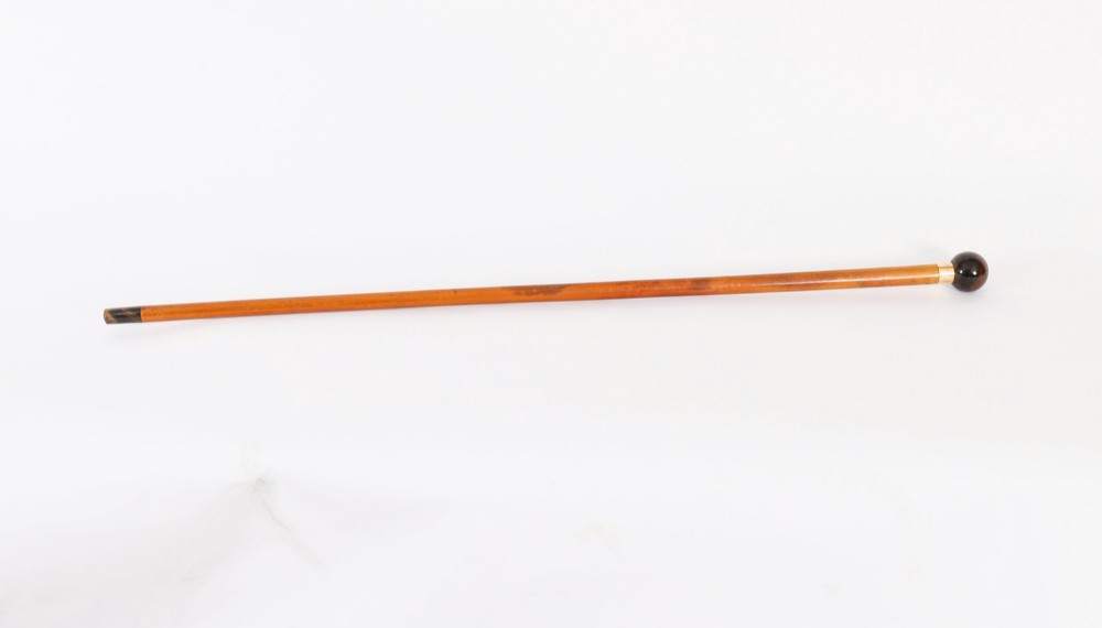 An antique Victorian wooden walking stick featuring a dark spherical pommel, an 18ct gold collar band, and a tapered brown shaft.