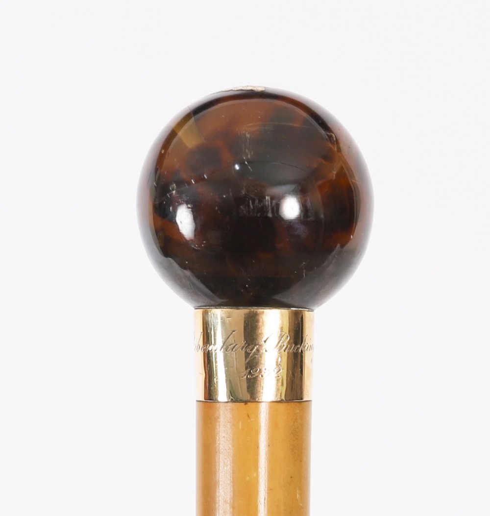An antique Victorian wooden walking stick featuring a dark spherical pommel, an 18ct gold collar band, and a tapered brown shaft. View V