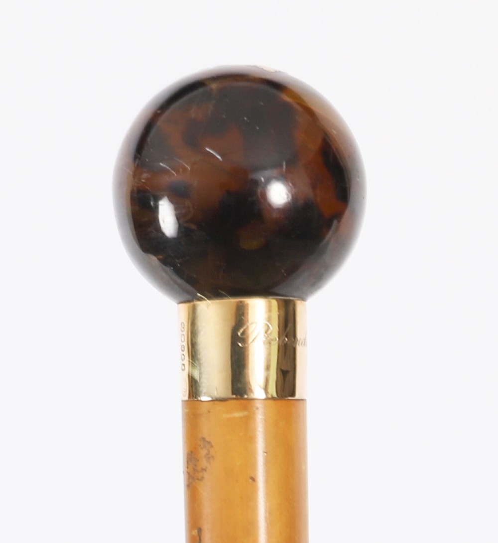 An antique Victorian wooden walking stick featuring a dark spherical pommel, an 18ct gold collar band, and a tapered brown shaft. View XI