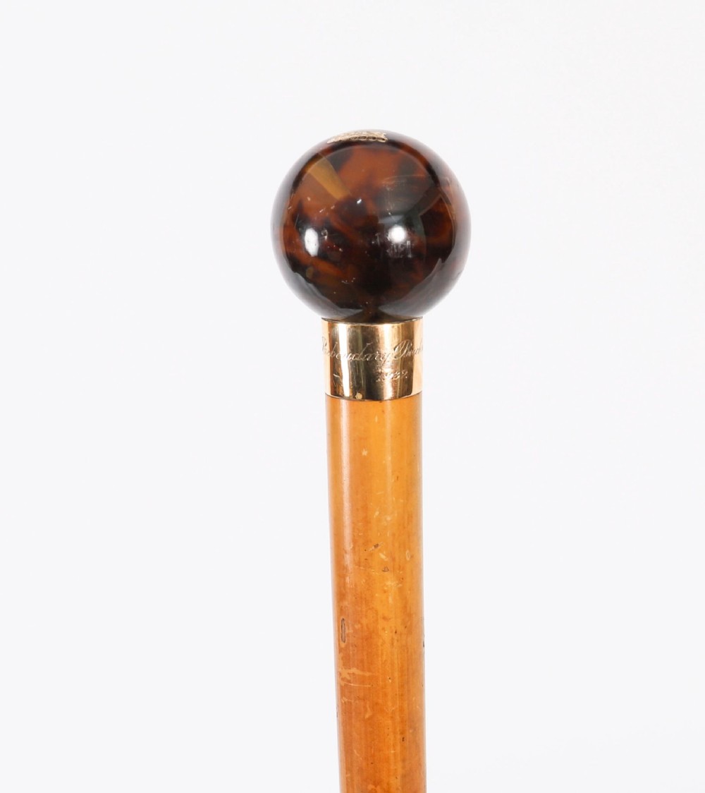 An antique Victorian wooden walking stick featuring a dark spherical pommel, an 18ct gold collar band, and a tapered brown shaft. View XII