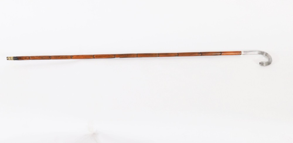 An antique walking stick featuring a fluted silver crook handle mounted on a dark polished wooden shaft. View II