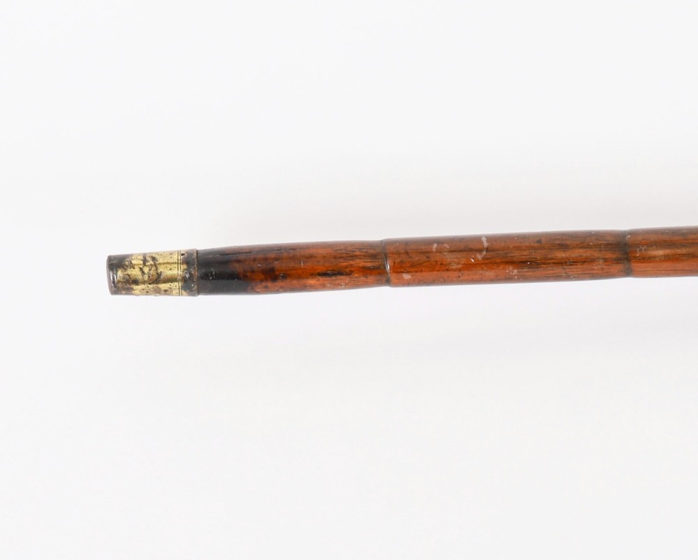 An antique walking stick featuring a fluted silver crook handle mounted on a dark polished wooden shaft. View V