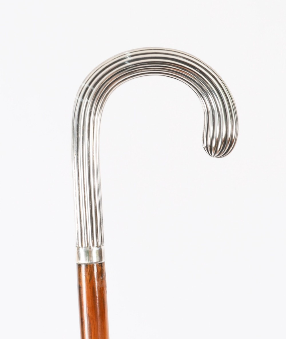 An antique walking stick featuring a fluted silver crook handle mounted on a dark polished wooden shaft. View VII