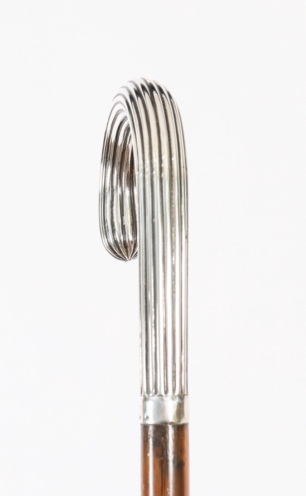 An antique walking stick featuring a fluted silver crook handle mounted on a dark polished wooden shaft. View VIII