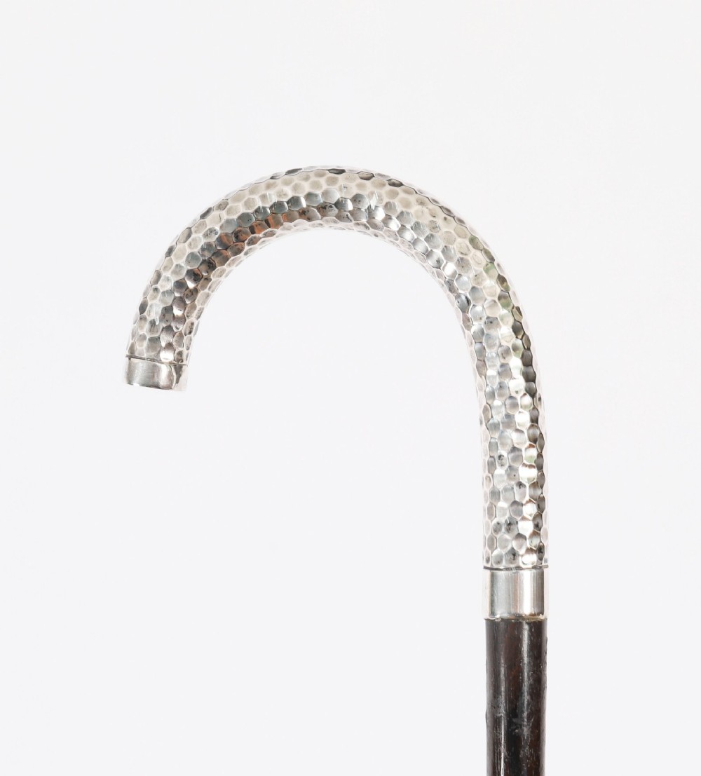 An antique French walking cane featuring a hand-hammered crook-shaped silver handle mounted on a dark wooden shaft. View V