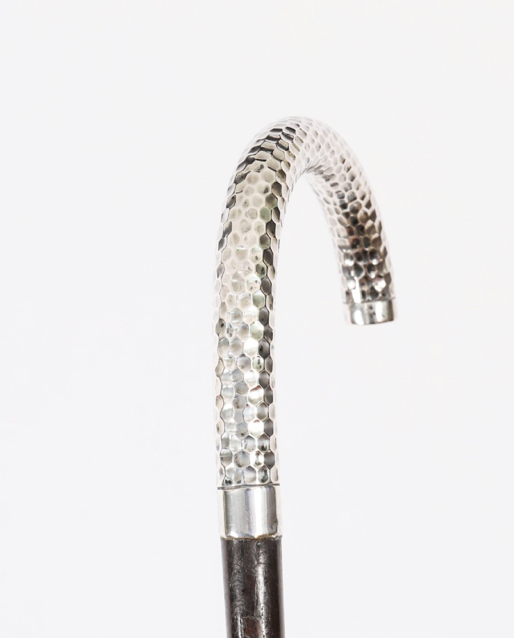 An antique French walking cane featuring a hand-hammered crook-shaped silver handle mounted on a dark wooden shaft. View VI