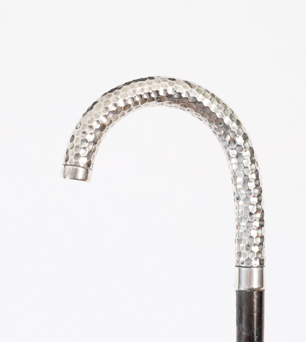 An antique French walking cane featuring a hand-hammered crook-shaped silver handle mounted on a dark wooden shaft. View X