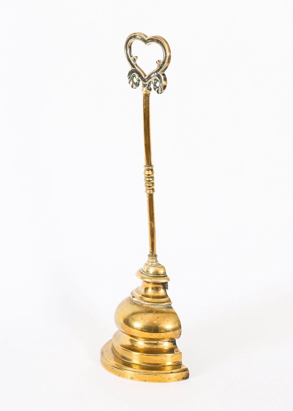 A 19th-century Victorian brass door stop featuring a tall shaft topped with a heart-shaped handle and supported by a heavy, tiered circular base. View II