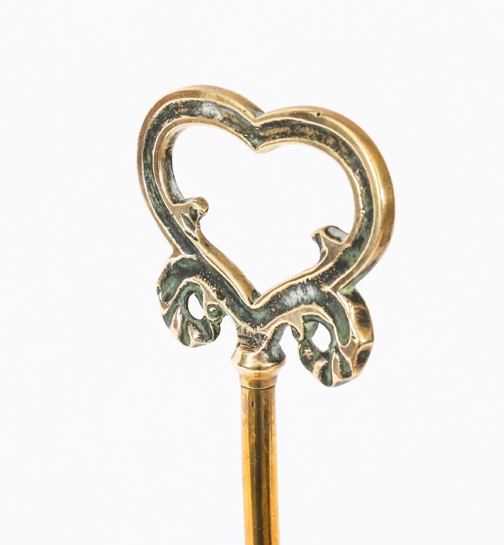 A 19th-century Victorian brass door stop featuring a tall shaft topped with a heart-shaped handle and supported by a heavy, tiered circular base. View III