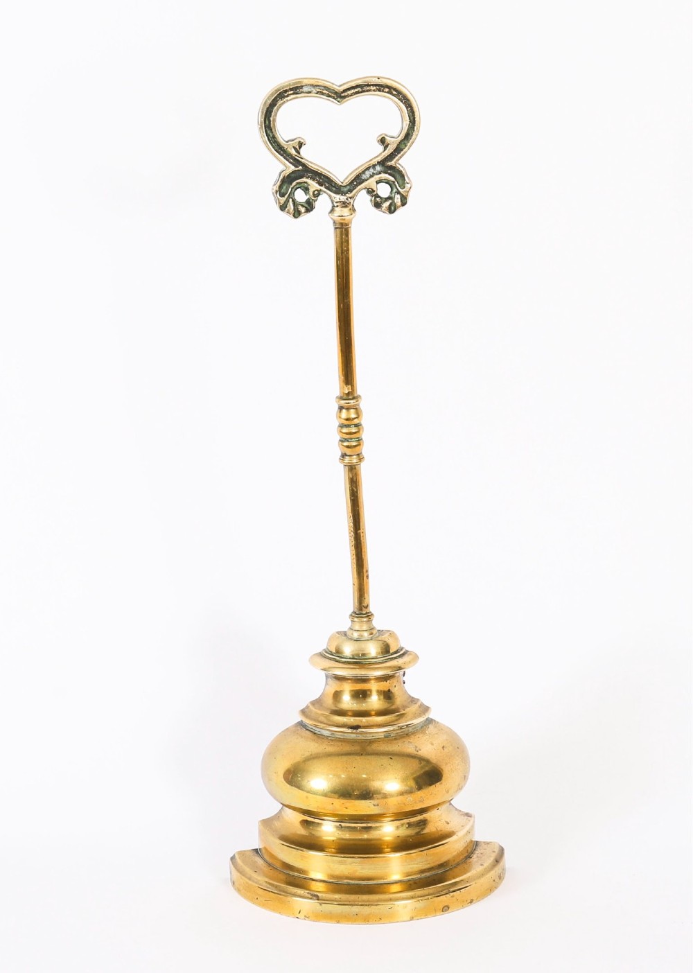 A 19th-century Victorian brass door stop featuring a tall shaft topped with a heart-shaped handle and supported by a heavy, tiered circular base. View IV