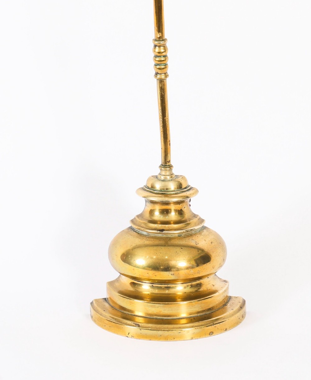 A 19th-century Victorian brass door stop featuring a tall shaft topped with a heart-shaped handle and supported by a heavy, tiered circular base. View X