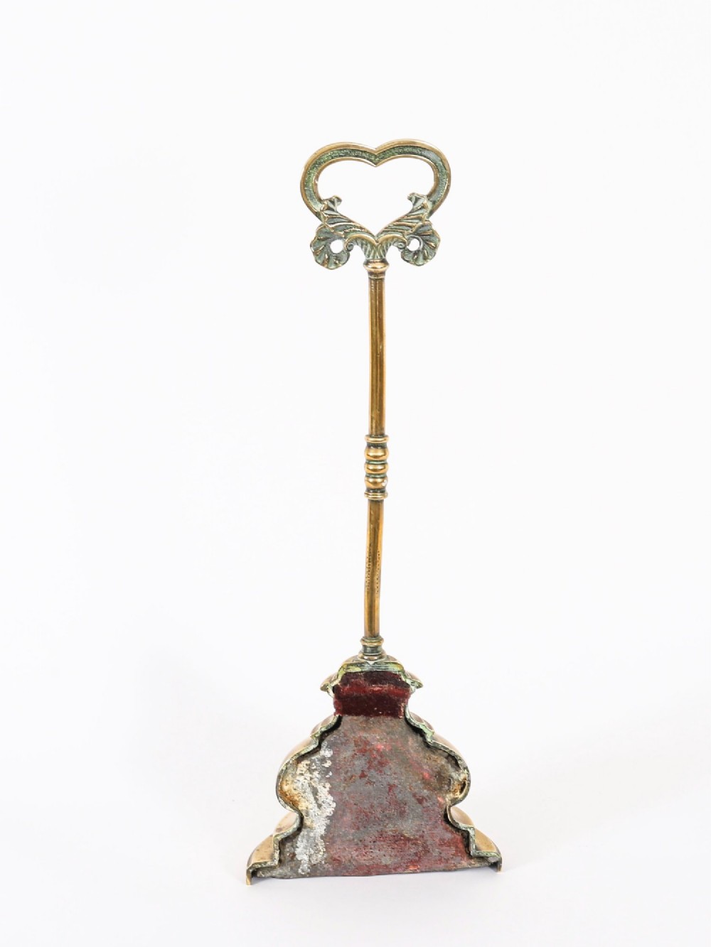 A 19th-century Victorian brass door stop featuring a tall shaft topped with a heart-shaped handle and supported by a heavy, tiered circular base. View XII