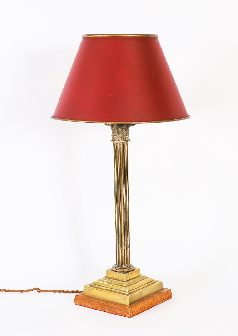 A pair of late nineteenth-century brass Corinthian column table lamps featuring fluted stems, stepped bases, wooden plinths, and conical red lampshades. View II