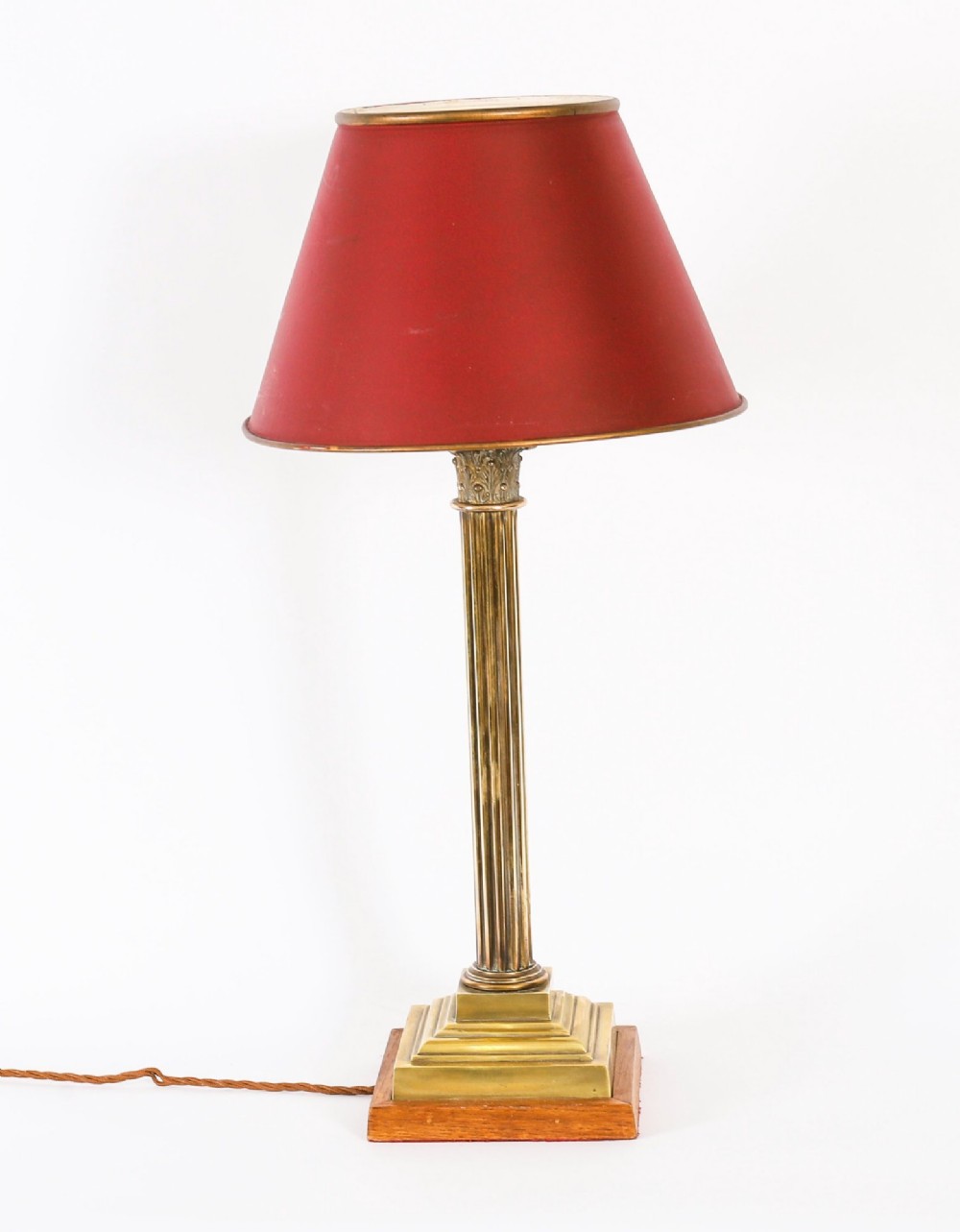 A pair of late nineteenth-century brass Corinthian column table lamps featuring fluted stems, stepped bases, wooden plinths, and conical red lampshades. View III