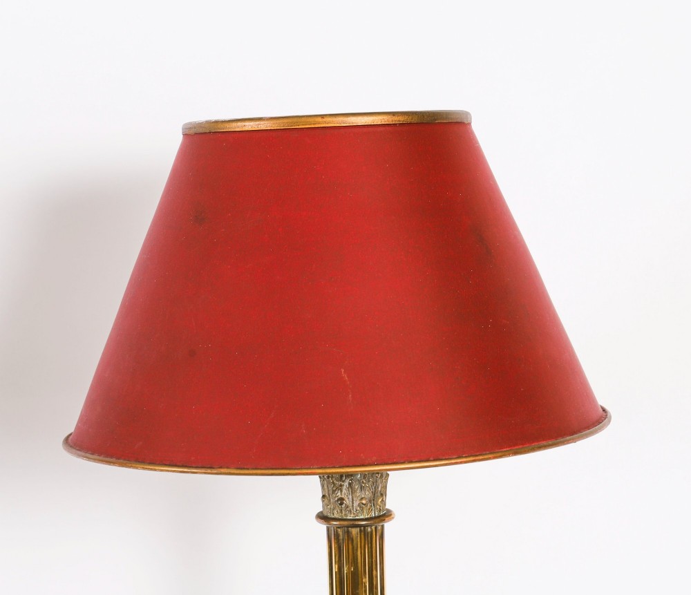 A pair of late nineteenth-century brass Corinthian column table lamps featuring fluted stems, stepped bases, wooden plinths, and conical red lampshades. View V