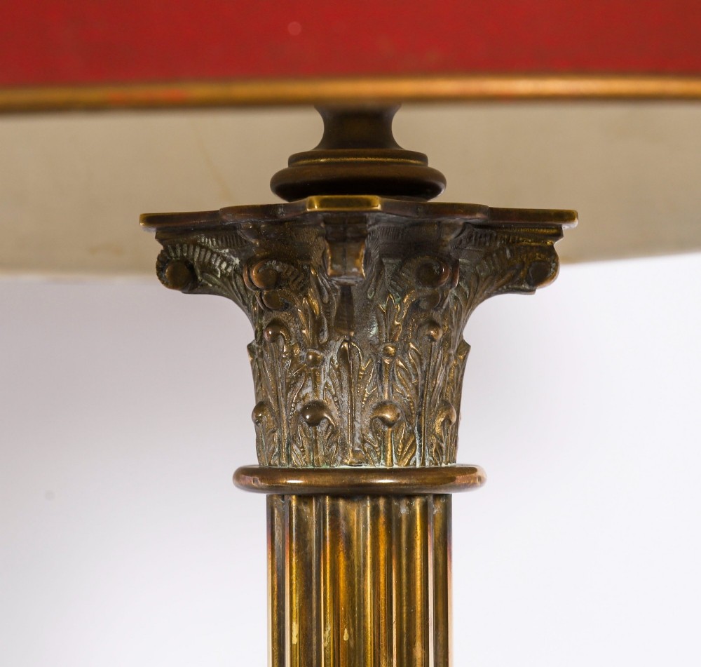 A pair of late nineteenth-century brass Corinthian column table lamps featuring fluted stems, stepped bases, wooden plinths, and conical red lampshades. View VII