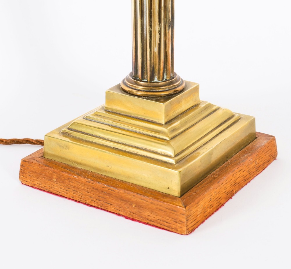 A pair of late nineteenth-century brass Corinthian column table lamps featuring fluted stems, stepped bases, wooden plinths, and conical red lampshades. View VIII