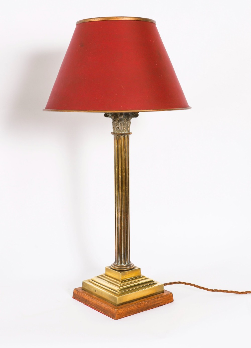 A pair of late nineteenth-century brass Corinthian column table lamps featuring fluted stems, stepped bases, wooden plinths, and conical red lampshades. View IX