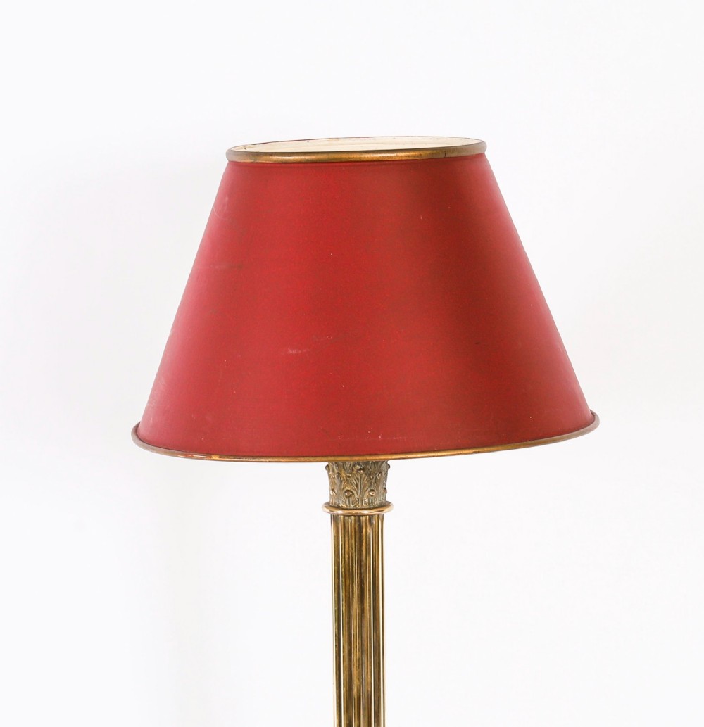 A pair of late nineteenth-century brass Corinthian column table lamps featuring fluted stems, stepped bases, wooden plinths, and conical red lampshades. View X