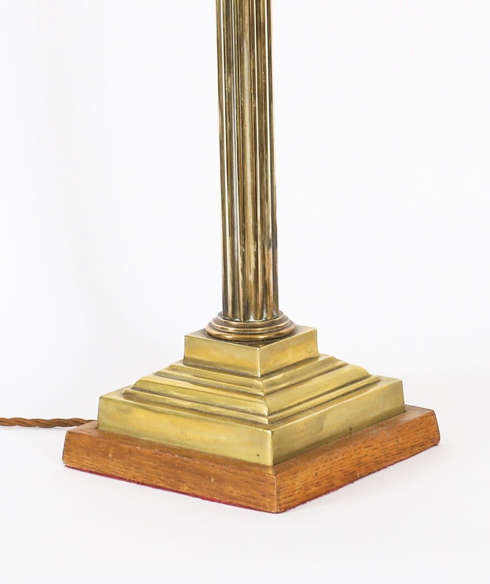 A pair of late nineteenth-century brass Corinthian column table lamps featuring fluted stems, stepped bases, wooden plinths, and conical red lampshades. View XIII