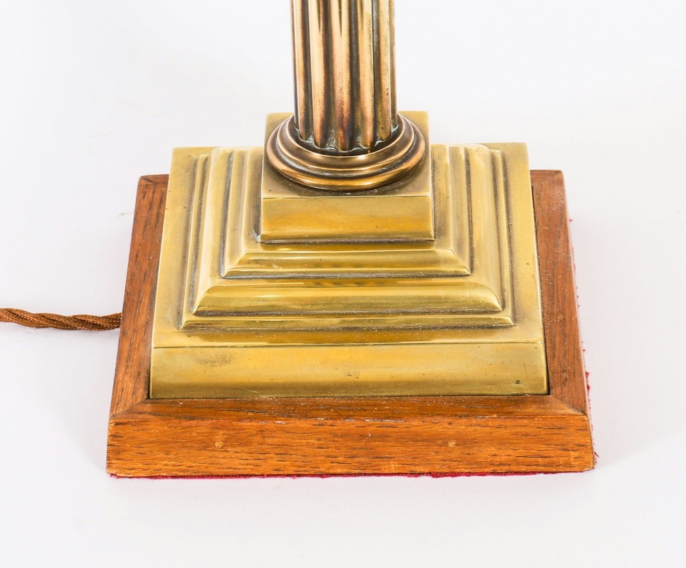 A pair of late nineteenth-century brass Corinthian column table lamps featuring fluted stems, stepped bases, wooden plinths, and conical red lampshades. View XIV