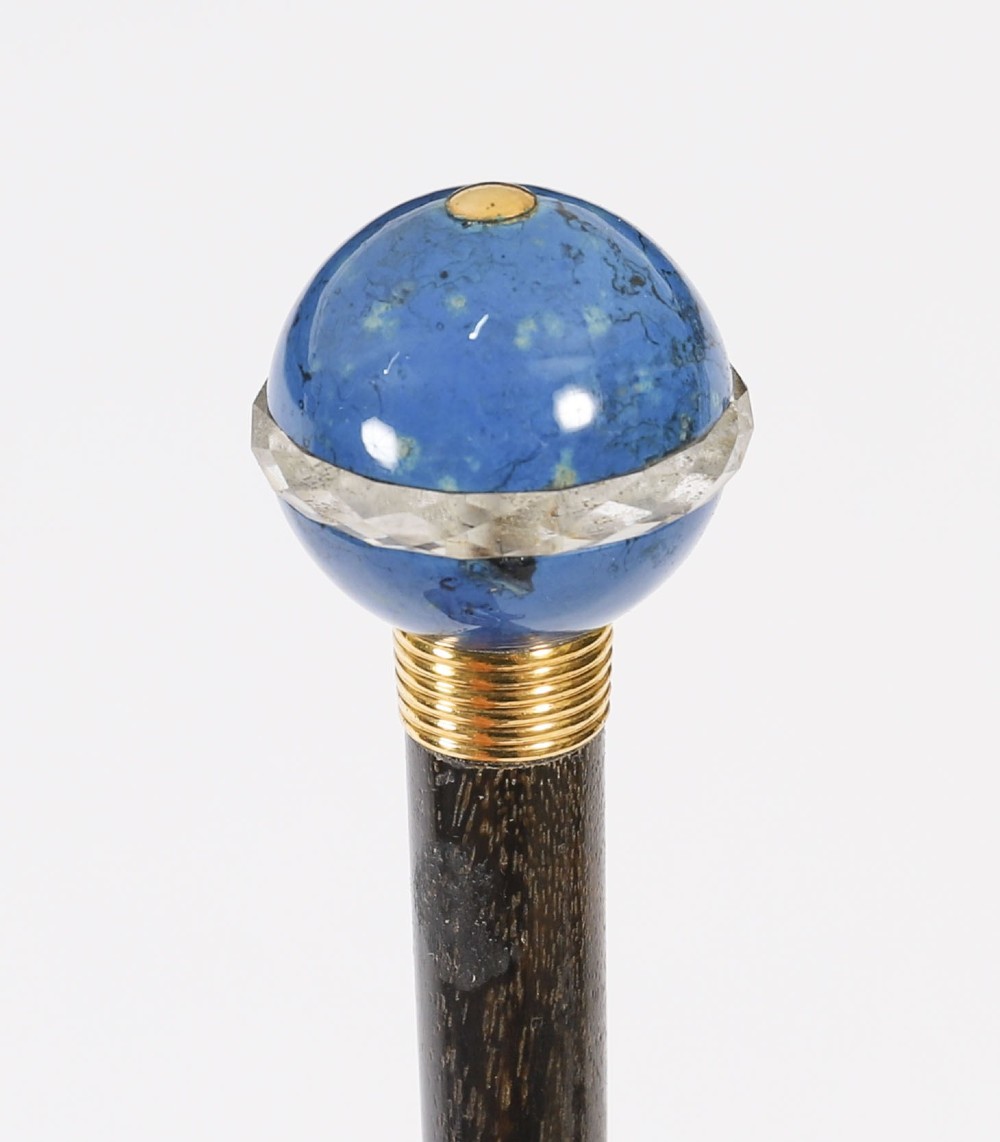 An Edwardian walking cane featuring a spherical lapis lazuli pommel accented with a faceted crystal band and a ribbed gold collar on a dark hardwood shaft.