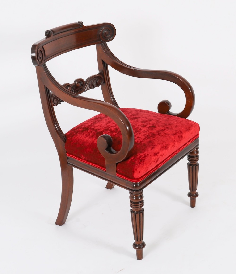 A set of ten Regency flame mahogany dining chairs with carved scroll backrails, turned fluted front legs, and red velvet seats. View II