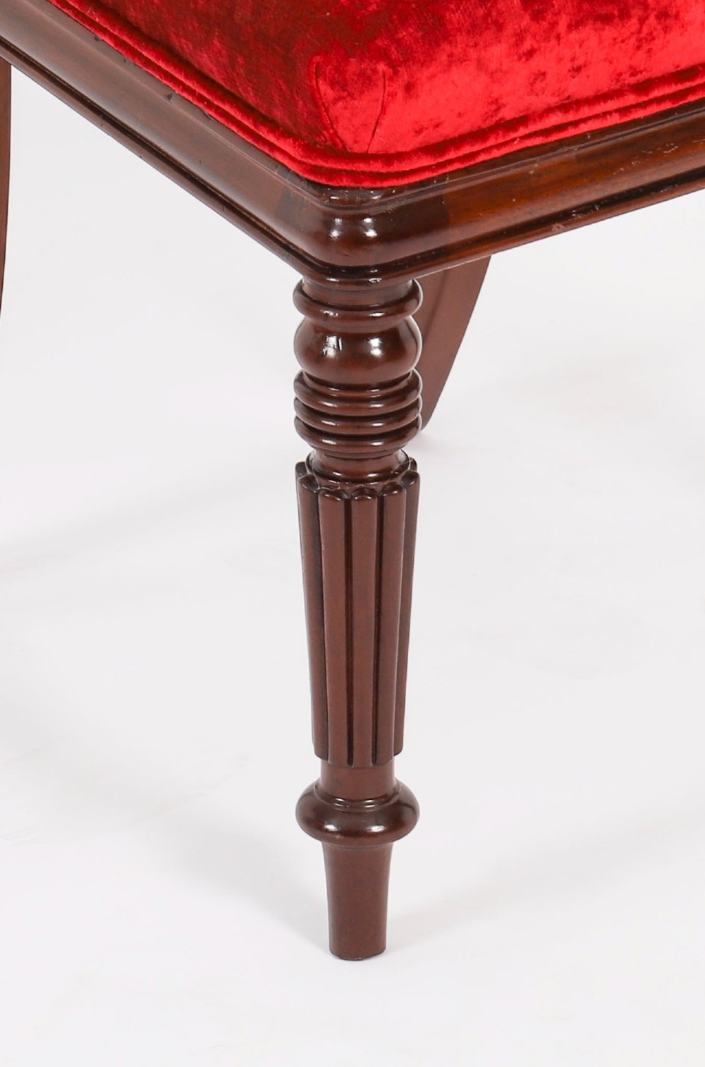 A set of ten Regency flame mahogany dining chairs with carved scroll backrails, turned fluted front legs, and red velvet seats. View VI