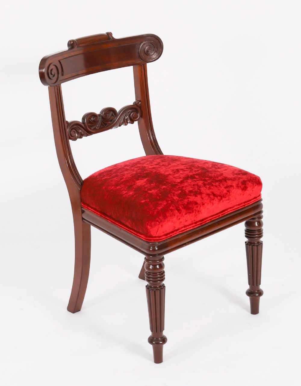 A set of ten Regency flame mahogany dining chairs with carved scroll backrails, turned fluted front legs, and red velvet seats. View VIII