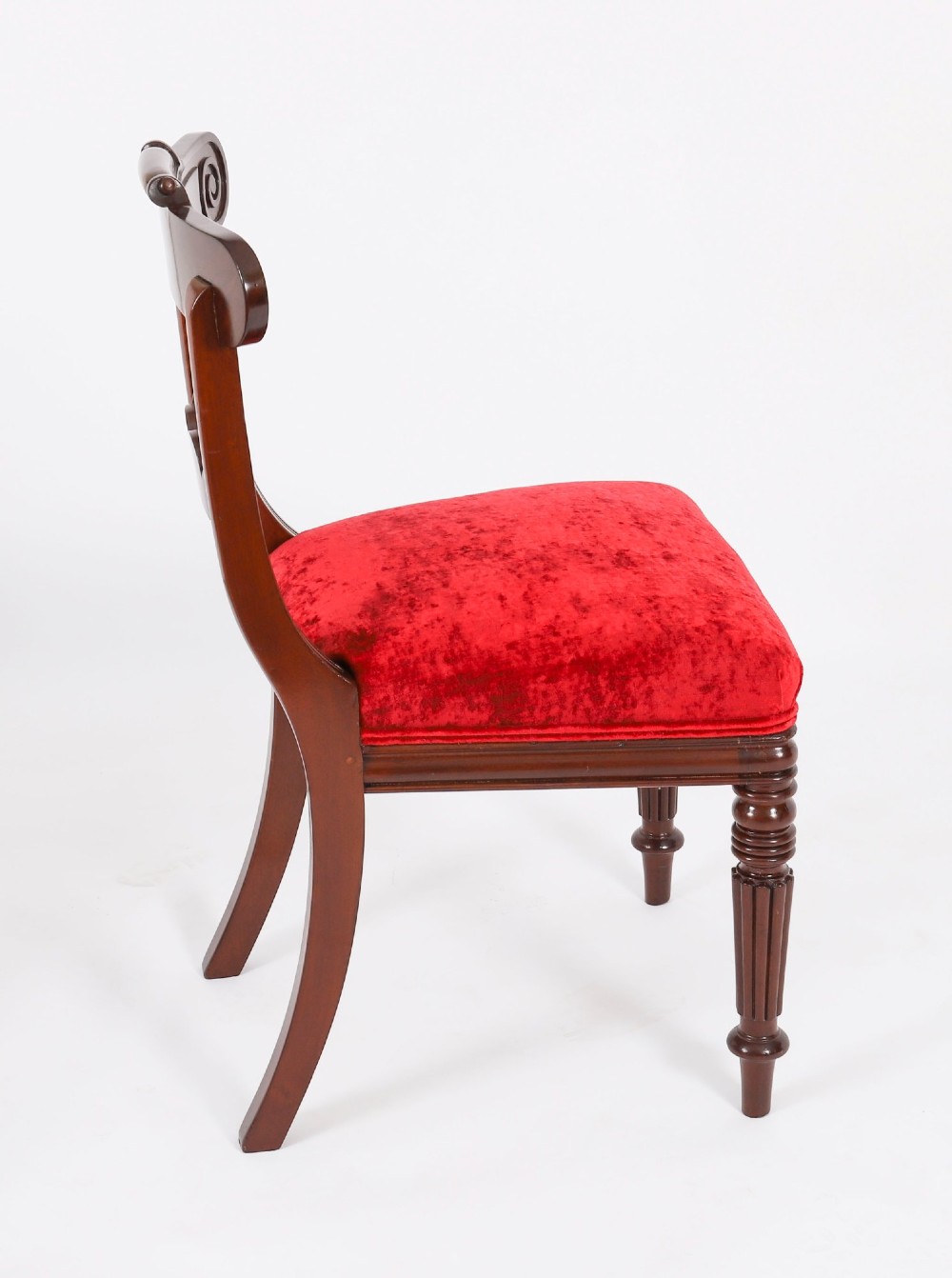 A set of ten Regency flame mahogany dining chairs with carved scroll backrails, turned fluted front legs, and red velvet seats. View IX